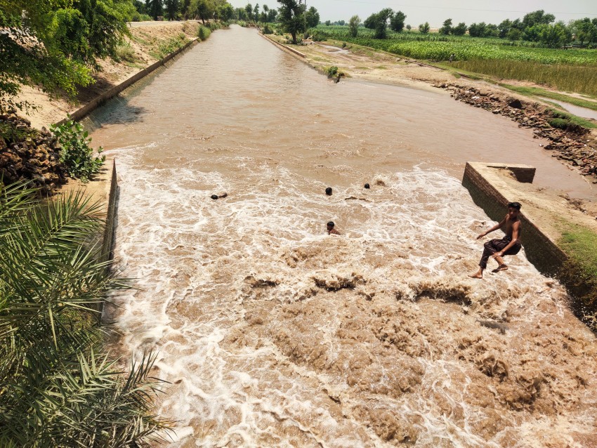 A child jumping to dive in the rapid flow of canal water.