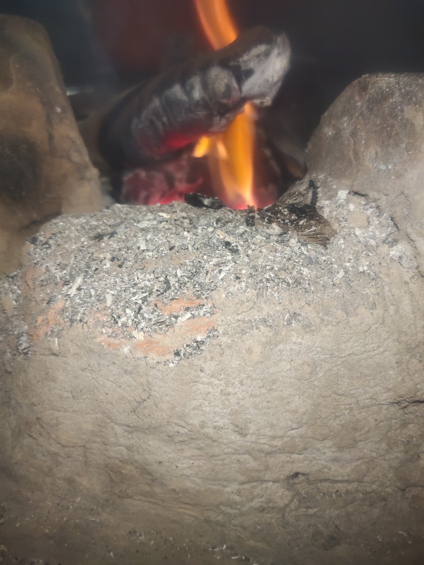 A close-up view of a fire burning in a house stove and the ash coming out of the fire