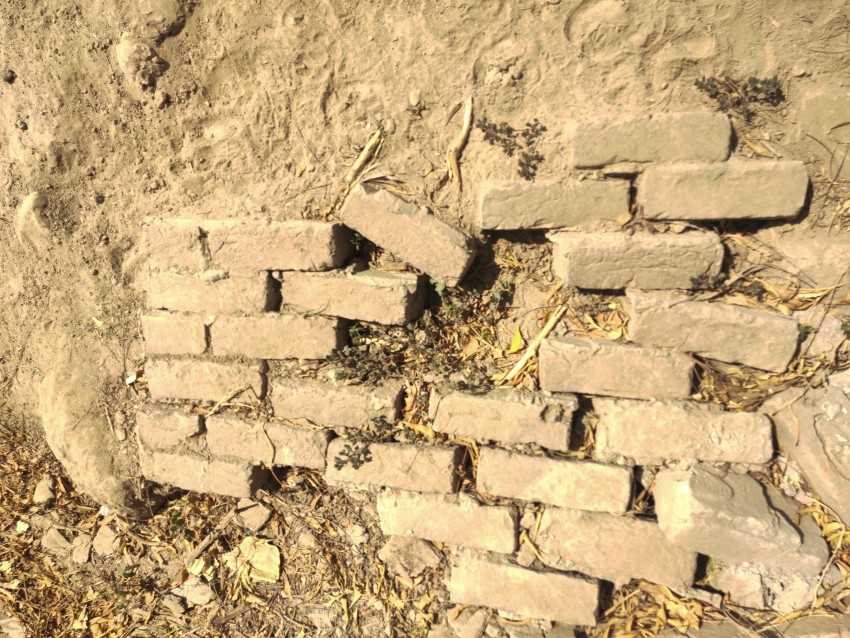 A few blocks of the fallen wall are now visible, the rest buried in the soil