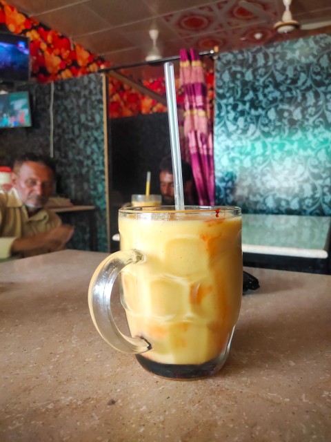 A glass of cold juice from fresh mangoes at a shop