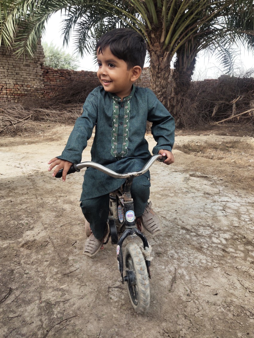 A little boy plays with a small bicycle at home.
