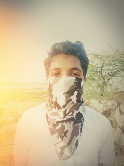 A masked boy standing on a mountain