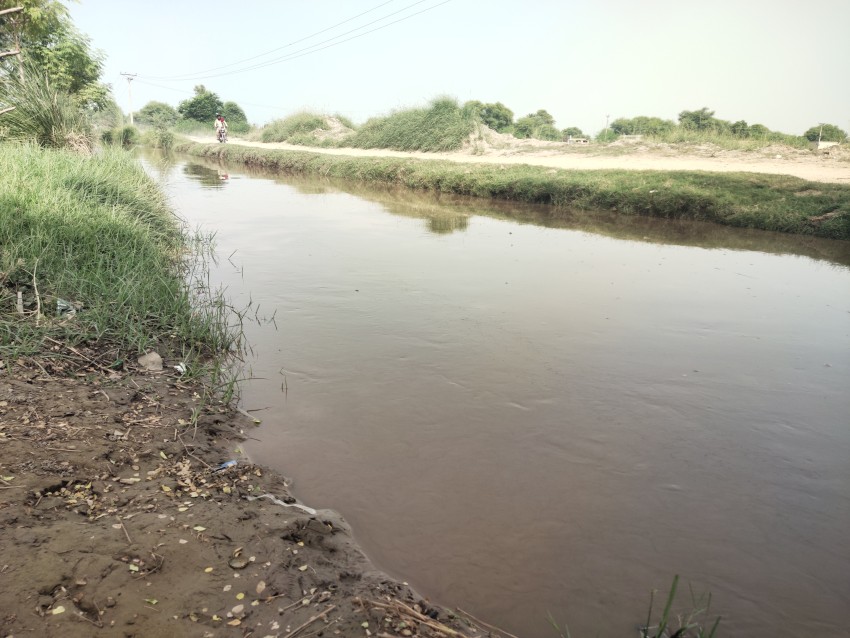 A motorcycle ride is coming along the flowing canal.