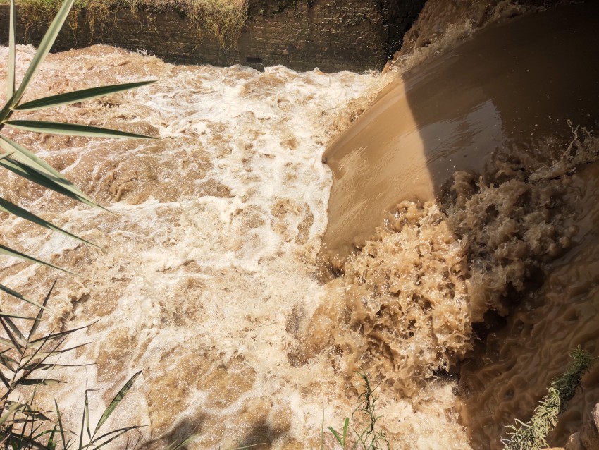 A rapid flow of water falling under a bridge