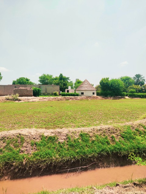 A round hut and canal portrait picture in a Pakistani village