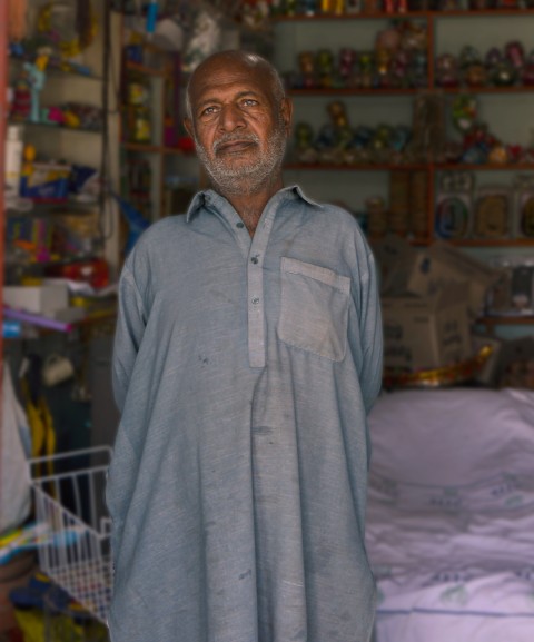 A shopkeeper standing for a pose with his inventory background.