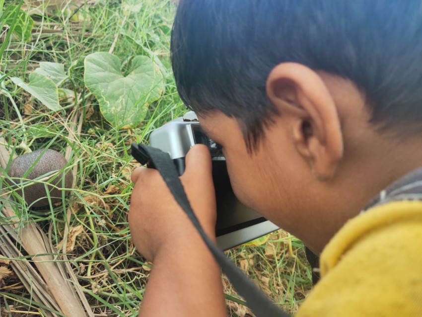 A small child is making a picture of a melon with the help of a camera