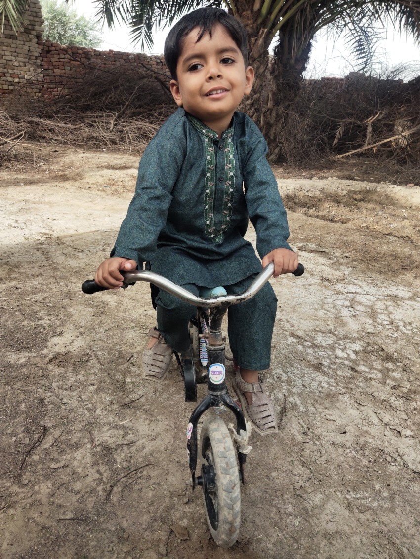 A small child is riding a bicycle in a house in Punjab and is very happy