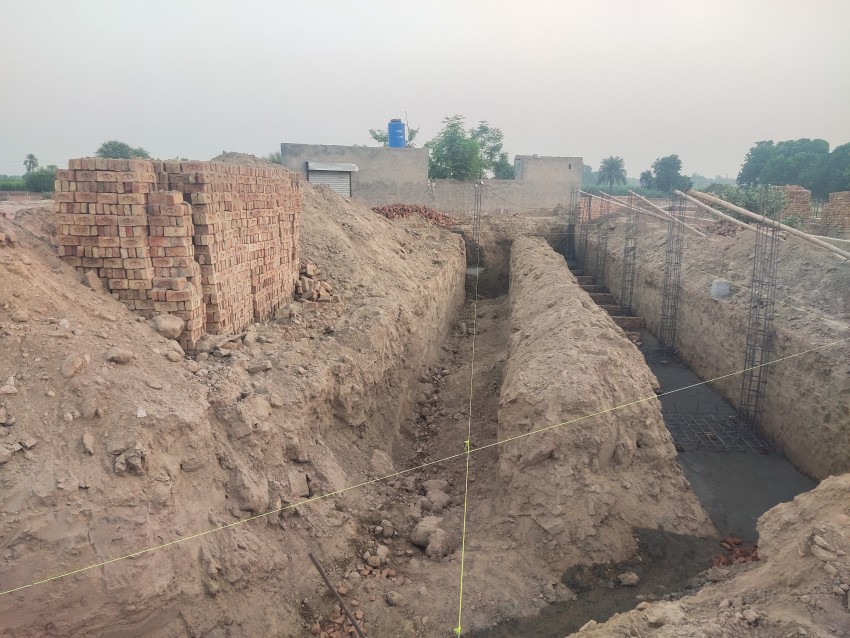 A view of the foundation where the iron pillar is being filled along with the measurement