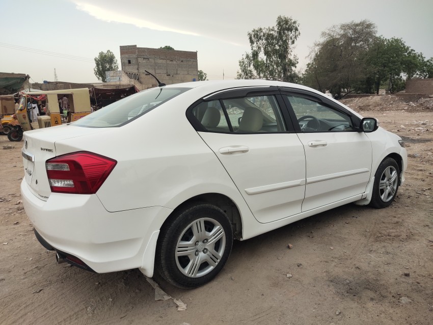 A white Honda City car parked in a ground