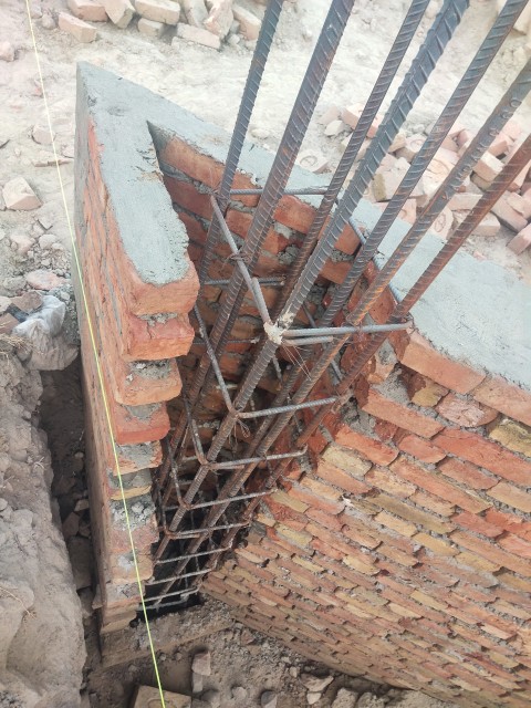 An iron pillar is being constructed along the wall in a triangular pattern.