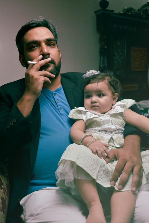 Baby photography   dad holding a baby on his lap with 2nd hand smoke