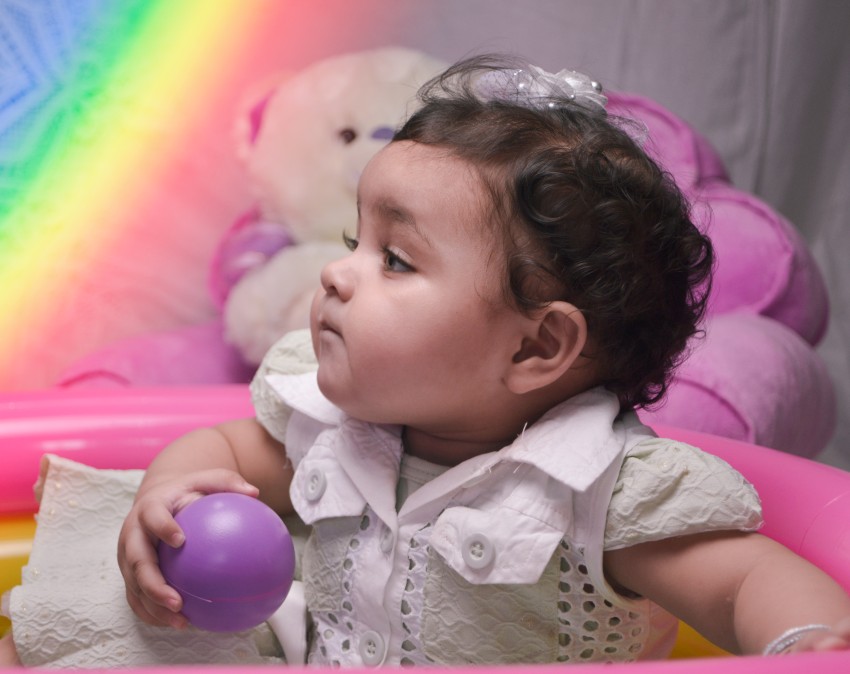 Baby photography   with purple ball in hand with rainbow colors