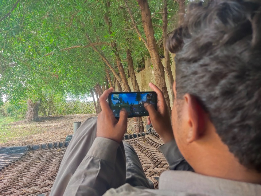 Back view of boy playing free fire game on mobile phone