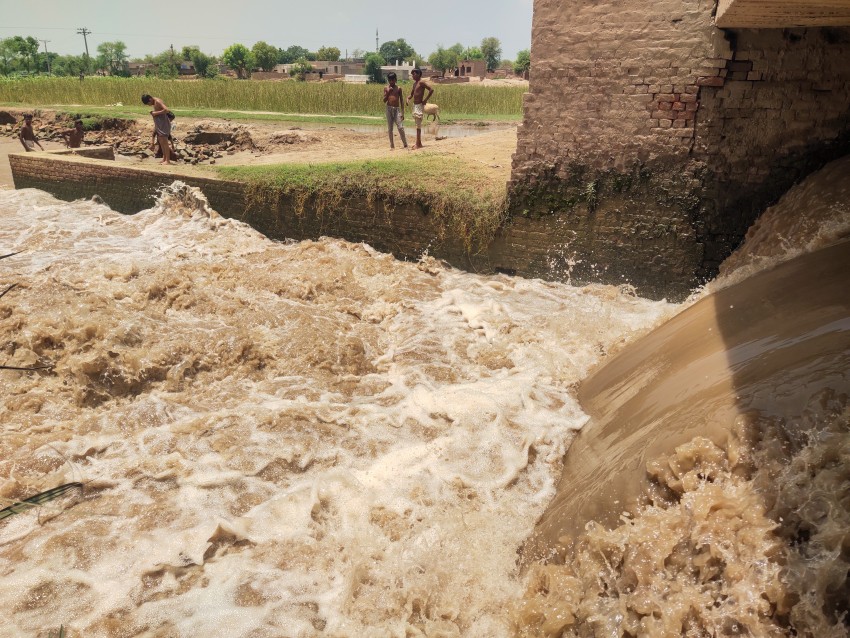 Children bathing in a stream of water flowing under a bridge