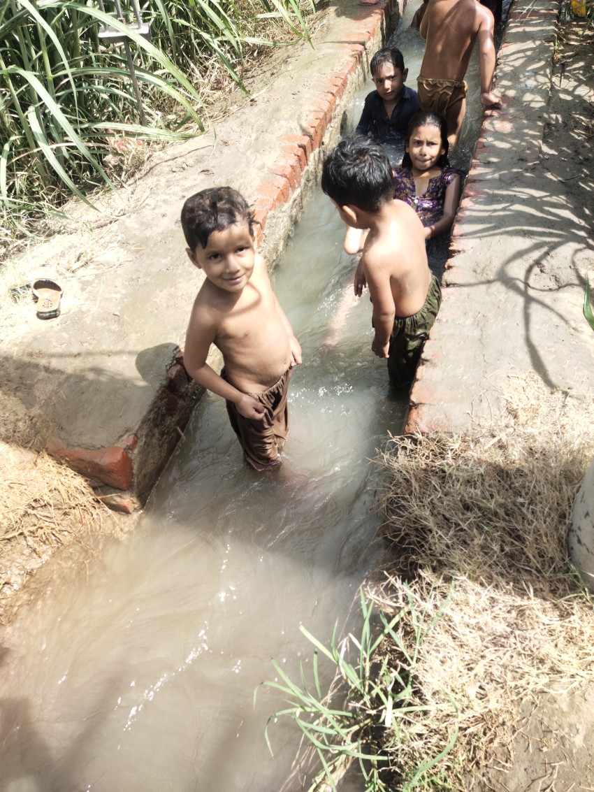 Children bathing in tubewell water in a small cement canal