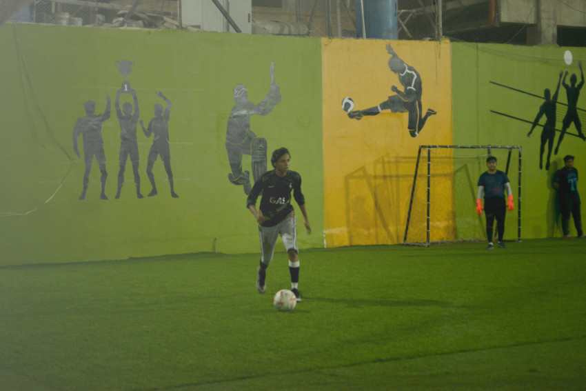 Futsal court Karachi player ready to hit ball in a green floor ground night match