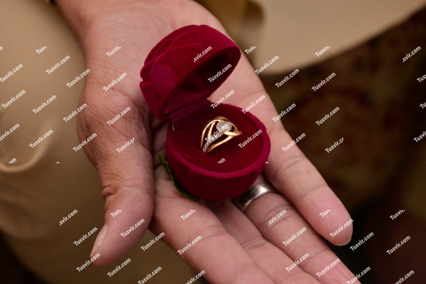 Groom right hand with wedding ring in a ring box on his palm proposing to a bride.