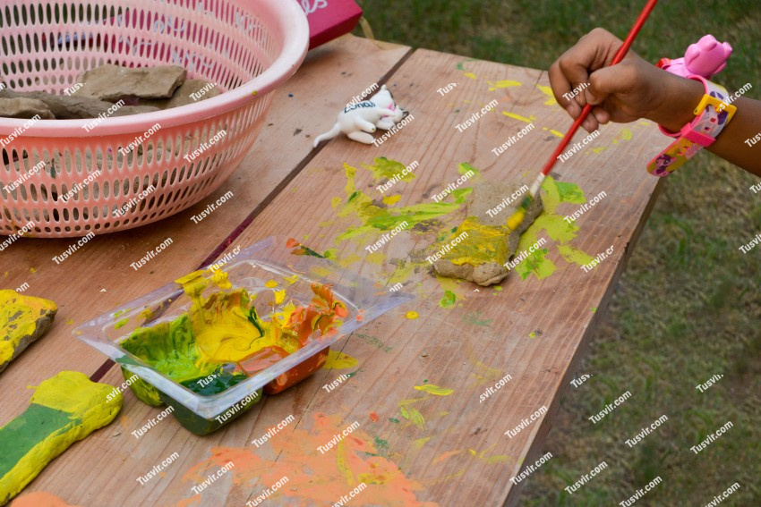 Kid painting on piece of rock