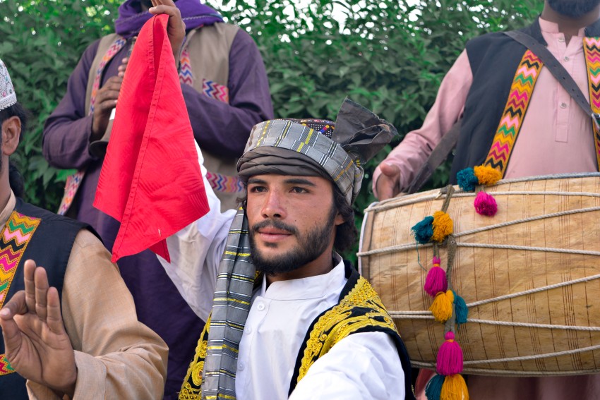 Perform posing with traditional clothes with hand drum in background
