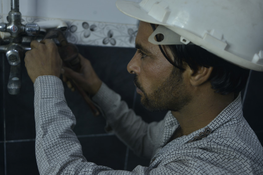 Plumber fixing water leak in water tap.