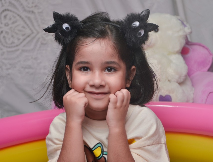Preschooler with both hands on cheek looking directly in the camera