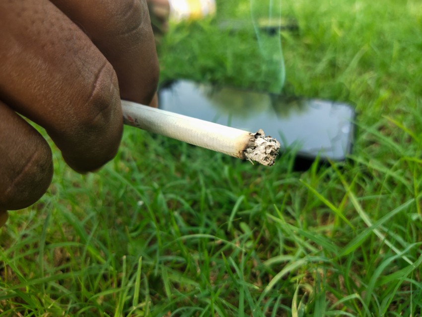 View of a man holding a cigarette in the park