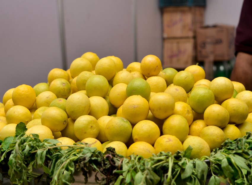 Yellow and mild green lemon served on a big tray with green leaves as a base
